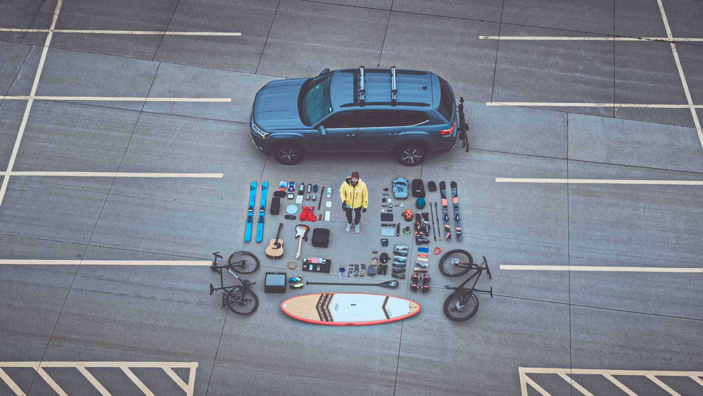 Michael Henry with his life laid out flat — bikes, skis, guitar, paddleboard, and the gear of a full life